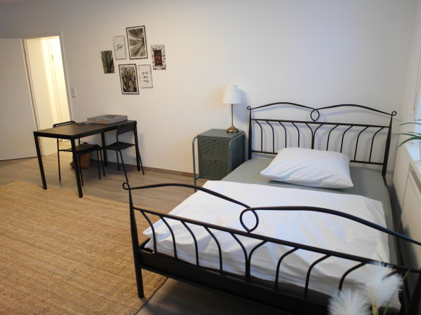Blick auf ein Bett und einen Tisch in einem Ein-Zimmer-Apartment