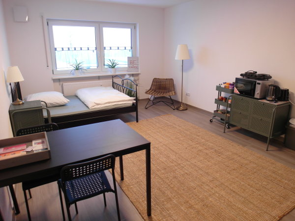 Blick auf Tisch, Bett und Kochmöglichkeit in einem Ein-Zimmer-Apartment