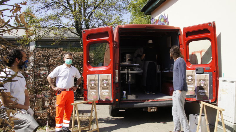 drei Personen stehen vor einem Kleintransporter